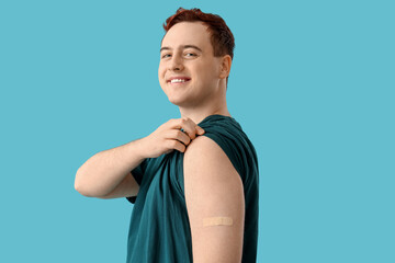 Happy young man with applied medical patch on blue background. Vaccination concept