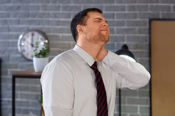 Businessman suffering from neck pain in office at night