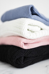 pile of sweaters and knits in different color fabric neatly folded and piled up