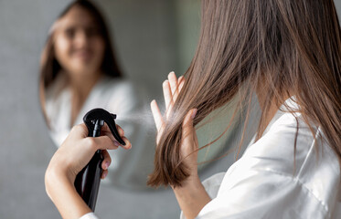 Haircare. Young Female Applying Hair Spray While Standing Near Mirror In Bathroom, Unrecognizable...
