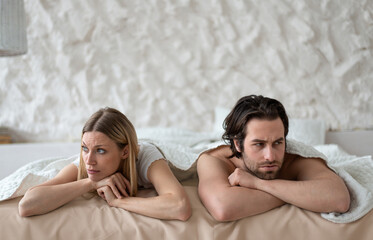 Sexual problems, relationship crisis. Stressed young couple lying in bed, overwhelmed with family...