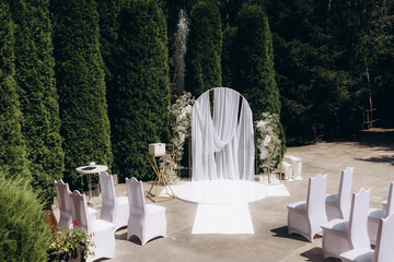 Elegant Outdoor Wedding Ceremony Setup with Stylish Decor and White Chairs