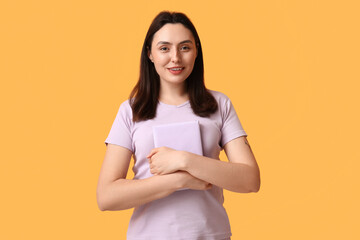Obraz premium Young happy woman with book on orange background
