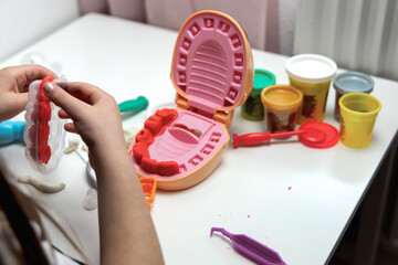 A child plays dentist and makes teeth out of plasticine