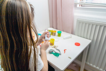 Little girl with long brown hair playing with plasticine
