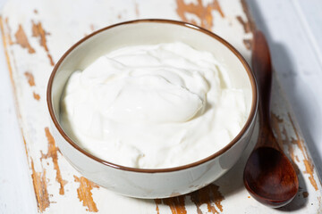 greek yogurt in a white bowl on a wooden board, top view