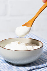 thick greek yogurt in a bowl and a spoon with yogurt, vertical closeup