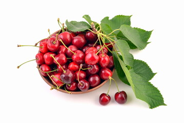 Fresh red cherries in bowl, with green leaves, isolated on white background.