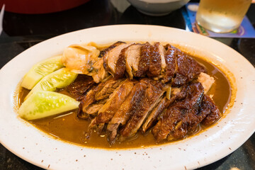 Close-up of roasted duck with crispy skin and juicy meat served on a white plate at a restaurant.