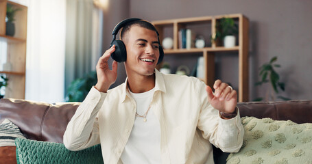 Man, happy and dancing with headphones on sofa for music, sound and streaming subscription in...