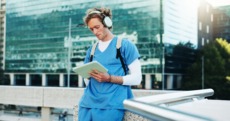 Medical student, city and man on tablet with headphones for education, audiobook and podcast. Technology, outdoor and healthcare nurse listen to music, learning or study on rooftop at college campus © KayExam/peopleimages.com