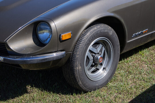 Close up of front wheel and headlight of datsun 260z parked on grass