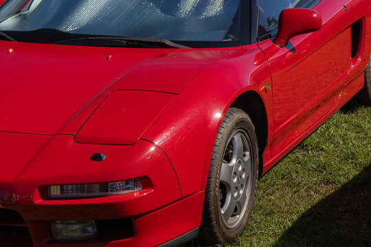 Red honda nsx parked on grass with sunshade on windshield