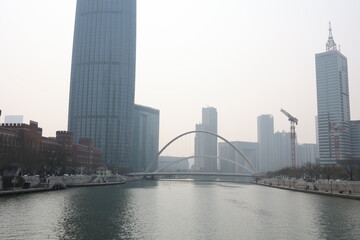 Fototapeta premium Urban skyline with modern buildings and a river in the foreground.