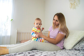 mother plays with baby on bed,hugs baby .happy childhood.