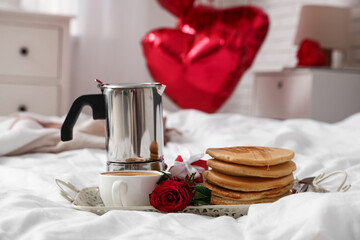 Tray with breakfast and rose for Valentine's Day on bed in room, closeup