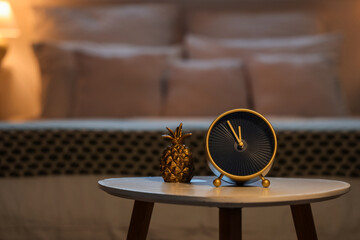 Alarm clock with decorative pineapple on table in bedroom at night, closeup
