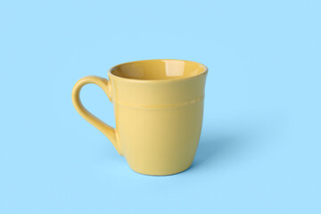Yellow empty ceramic mug on blue background