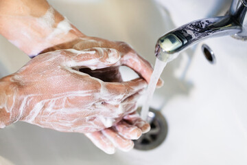 A man washes his hands with soap in the bathroom. Personal hygiene. Disinfection and precautions during a pandemic