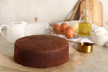 Tasty chocolate sponge cake with ingredients on light grunge background