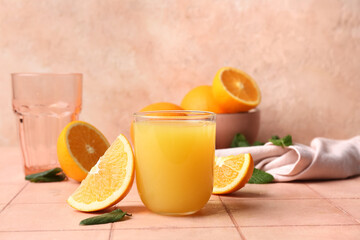 Glass of tasty juice with orange slices and mint leaves on beige tile table