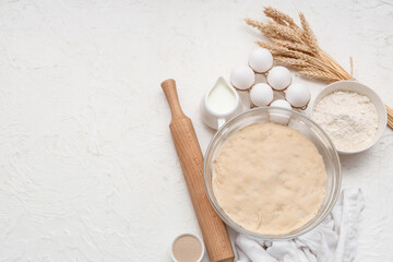 Composition with wooden rolling pin, dough and ingredients on white background