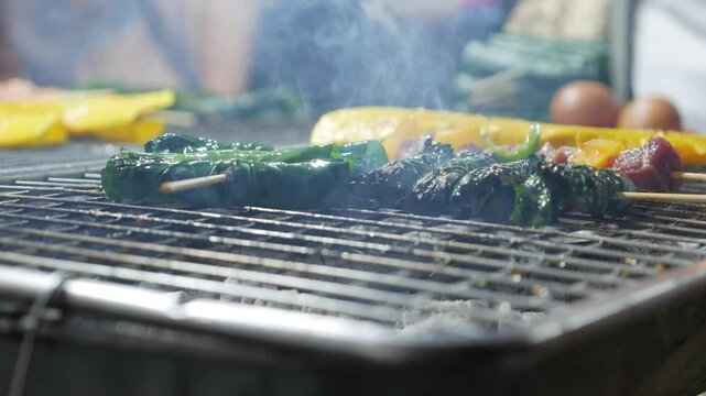 Bo la lot, or beef wrapped in betel leaves, roasts over glowing coals, its rich aroma filling the air. A beloved Vietnamese street food delight.