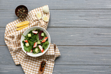 Bowl of salad with crab sticks, spinach and cucumber on grey wooden background © Pixel-Shot