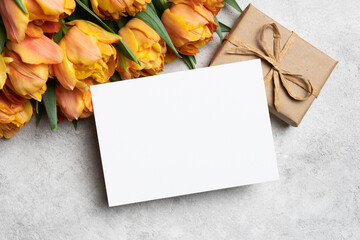 Blank greeting card mockup with tulips flowers bouquet and gift box