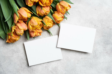 Blank invitation cards mockup front and back sides, tulips flowers bouquet on grey concrete background, flat lay with copy space for card design
