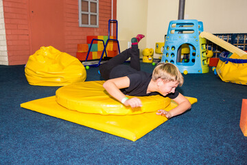 boy 9 years old, lying down, spinning on sports equipment, doing sports, sportswear, training, gym,...