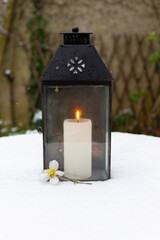 Black Lantern and candle on a snow covered table.