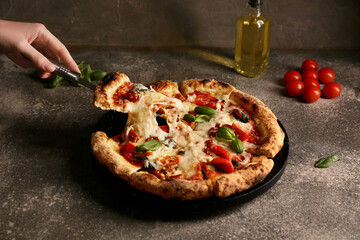 Hand taking slice of tasty pizza Margarita on grunge background