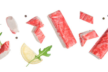 Cut tasty crab sticks with arugula leaf, peppercorns and slice of lemon flying on white background © Pixel-Shot