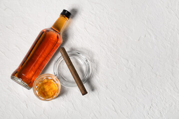 Bottle and glass of cold rum with cigar on white background