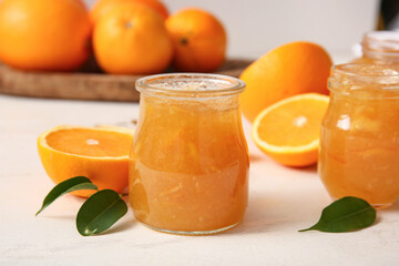 Jar of tasty orange jam on white wooden background