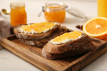 Tasty sandwiches with butter and sweet orange jam on board, closeup