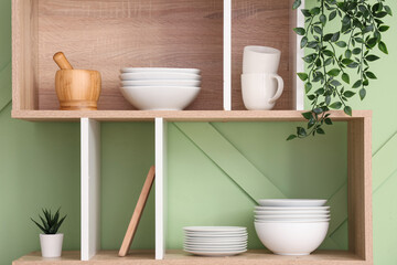Shelves with clean plates and bowls in stylish kitchen, closeup