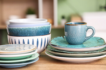 Clean plates, bowls and cup on wooden counter in kitchen, closeup