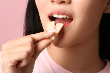 Pretty young Asian woman with open mouth holding chewing gums on pink background, closeup