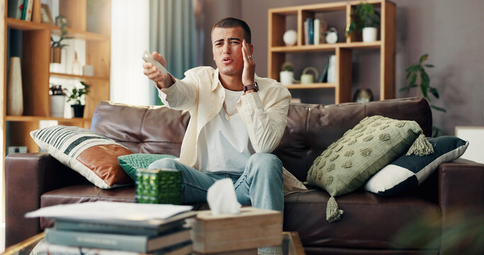 Frustrated, man and watching tv with headache on sofa for bad game, news or entertainment at home. Male person, wrong channel or program with remote, pain or dislike for online streaming at house
