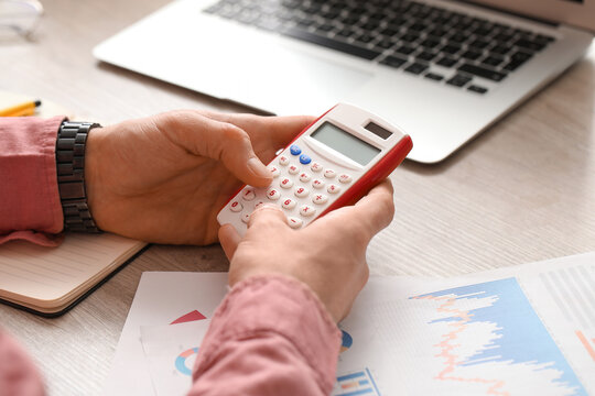 Male hands using calculator in office. Closeup