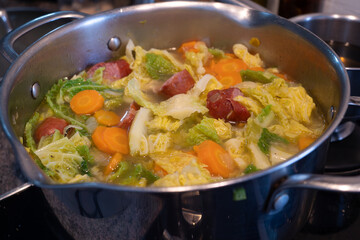 A pot of soup with vegetables and meat in it