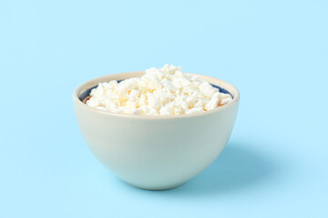 Bowl with fresh cottage cheese on blue background