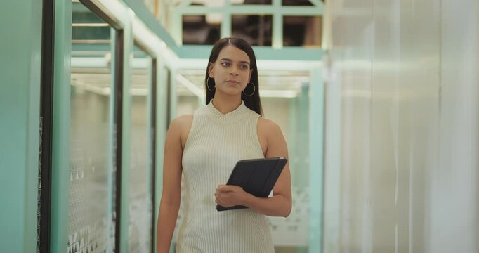 Indian happy young adult gen z busy boss woman ceo lady hold tablet walk indoor office hall way space Asian smiling modern expert girl intern female staff use device leave campus work place day time