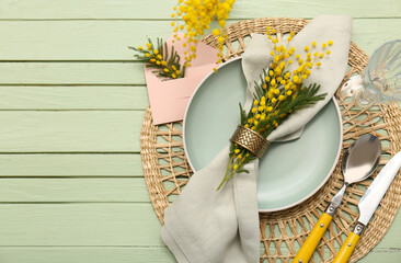 Beautiful table setting with mimosa flowers on green wooden background