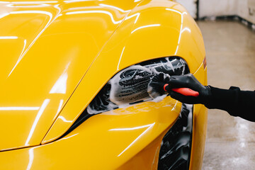 Detailing car headlights cleaning with foam and soft brush. Process of detailing sports car...