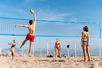 Friends playing beach volleyball on sunny summer day