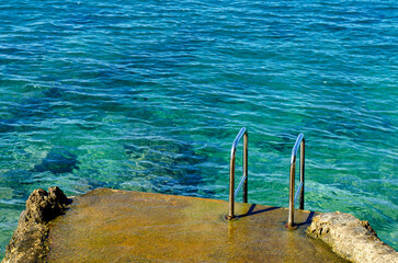 Ladder leading into the sea on a sunny day
