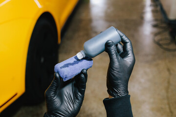 Process of pouring ceramic liquid from bottle on sponge to apply a protective nano layer on car....